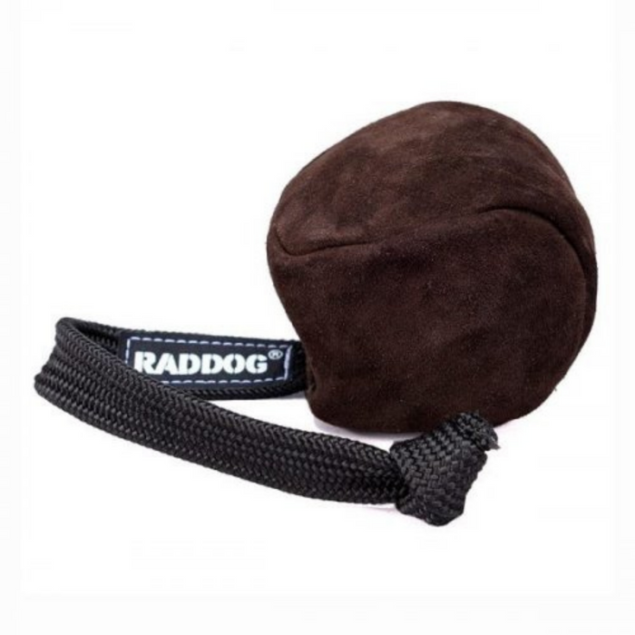 Brown leather dog training ball with a soft, rounded shape and a black braided rope handle, featuring a “RADDOG” label, isolated on a white background.