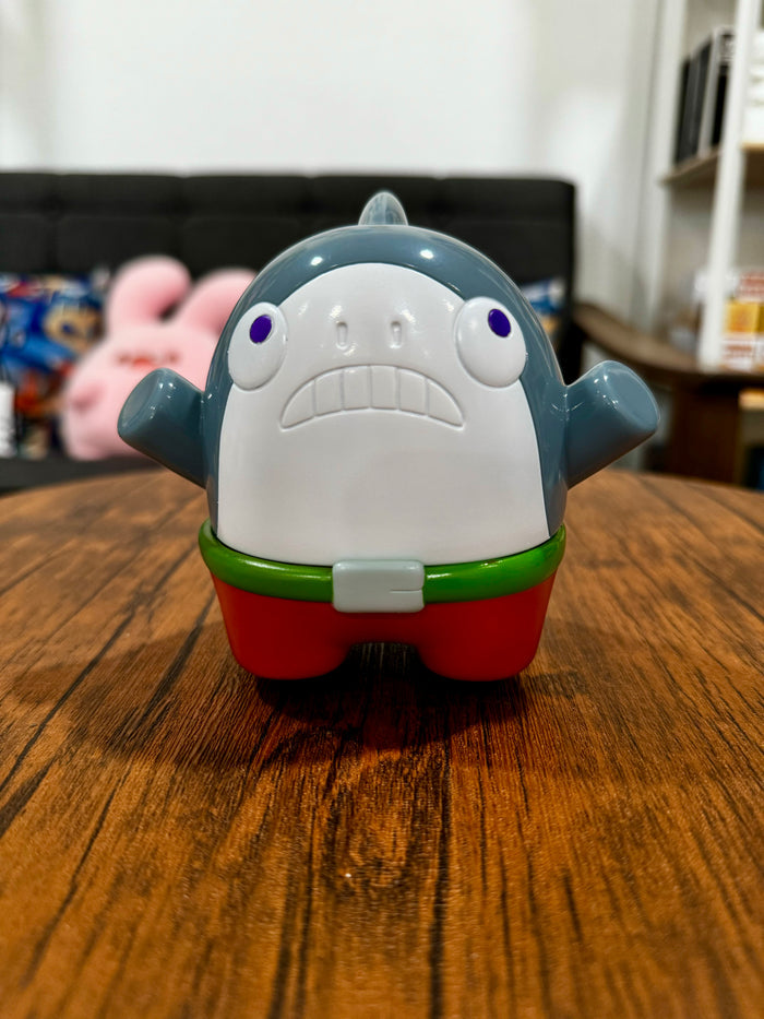A baby toy shark figure, Sofubi material, 11.5cm size, indoor setting. Reflects Strangecat Toys' blind box and art toy store essence.