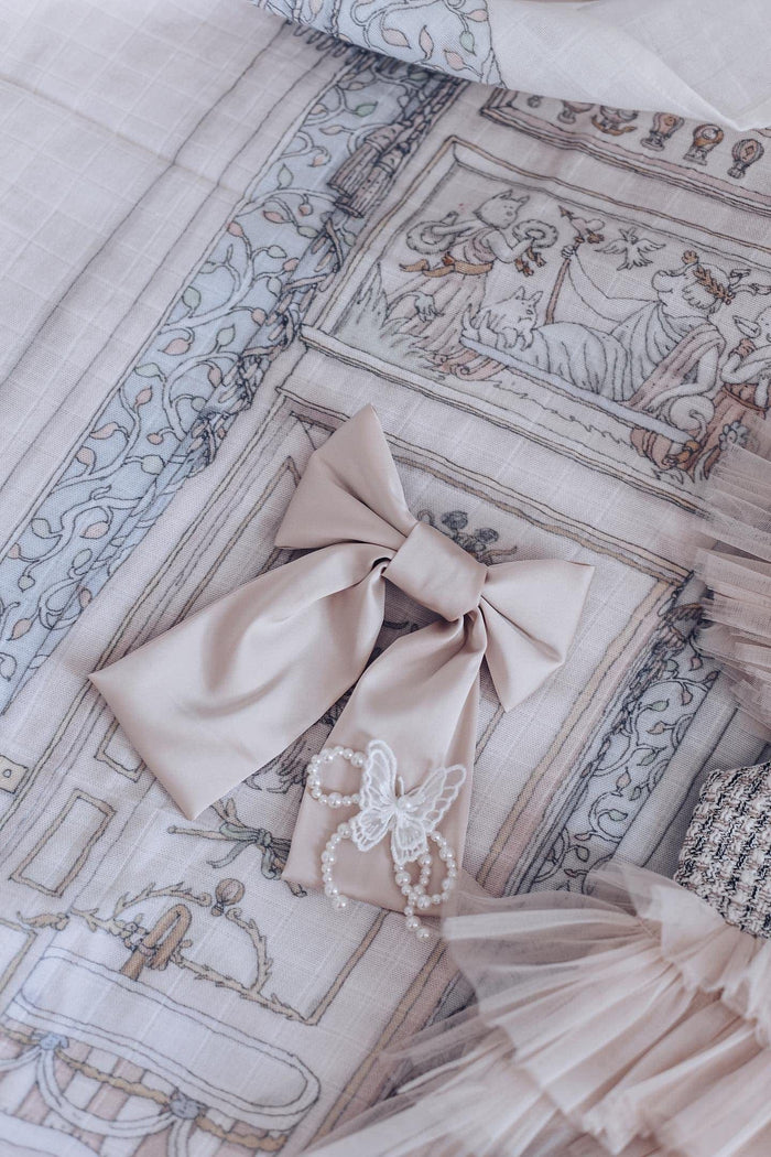 Close up view of Anise Satin Embroidered Hair Bow in champagne with butterfly detail