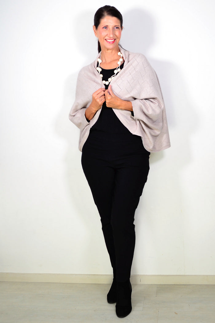 Peony beige travel cardigan wrap draped over a chair, showcasing its soft knit fabric and versatile style.