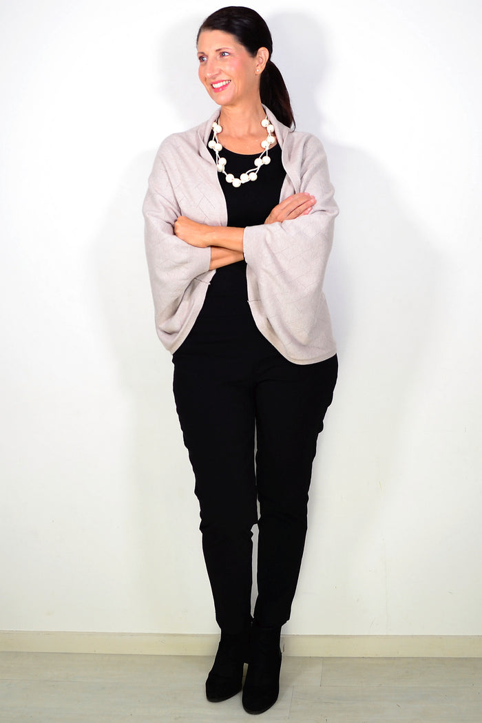 Peony beige travel cardigan wrap draped over a surface, showcasing soft fabric and stylish design for comfortable travel wear.