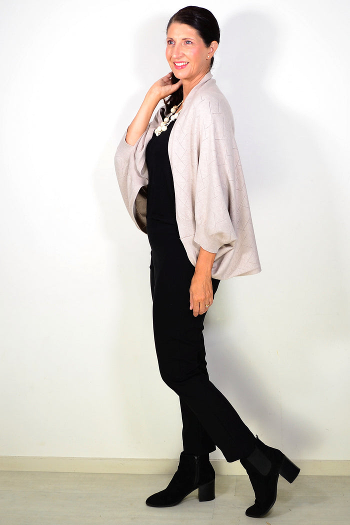 Beige Peony travel cardigan wrap draped over a chair, soft fabric, cozy and versatile for travel or casual wear.