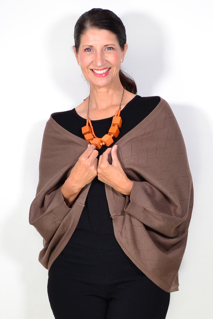 Peony brown travel cardigan wrap displayed draped over a surface, showcasing its soft fabric and cozy design.
