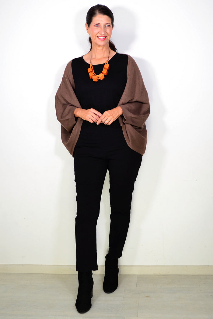 Brown Peony travel cardigan wrap draped over a chair, showcasing its soft fabric and cozy, versatile design.