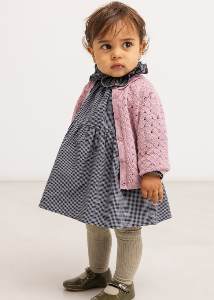 Black striped dress with a flared edge and long sleeves, paired with a pink jacket.