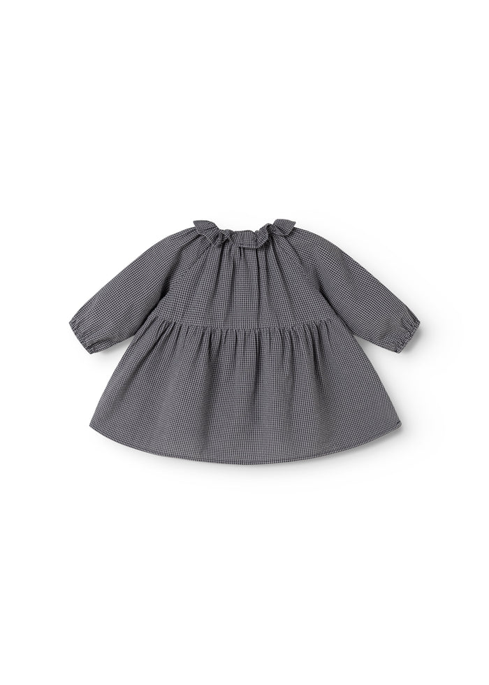 Dark checkered baby dress with a ruffled chest and flowing skirt, long sleeves.