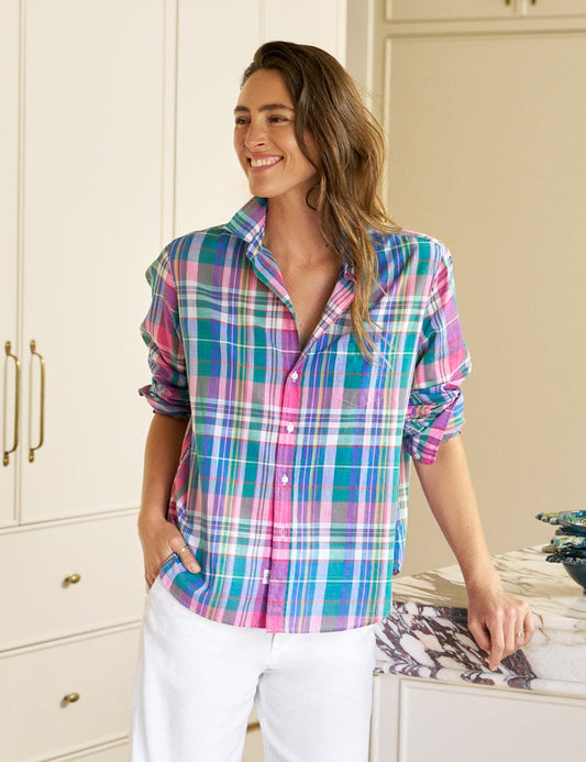 Woman wearing a colorful plaid shirt and white pants in a kitchen.