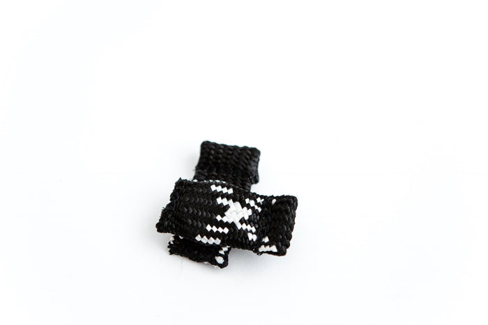Braided black and white dog training tug toy with compact cylindrical shape, designed for bite work and interactive play.