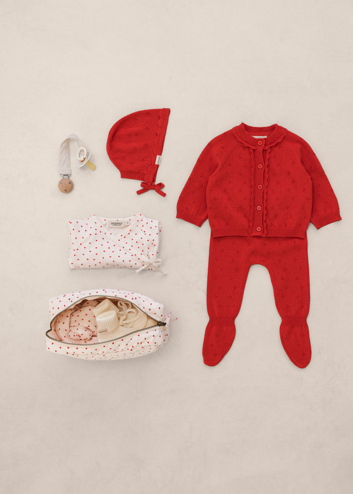 Red baby set with cardigan, pants, hat, and accessories