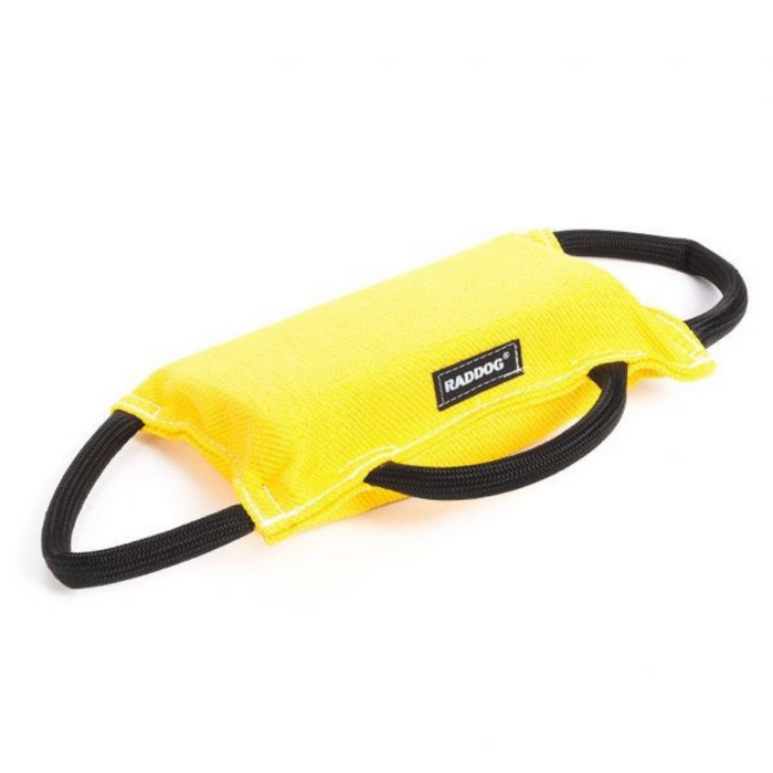Yellow padded dog training bite tug with a textured fabric surface, white stitching along the edges, a black “RADDOG” label on the side, and two black rope handles on each end, displayed against a light background.