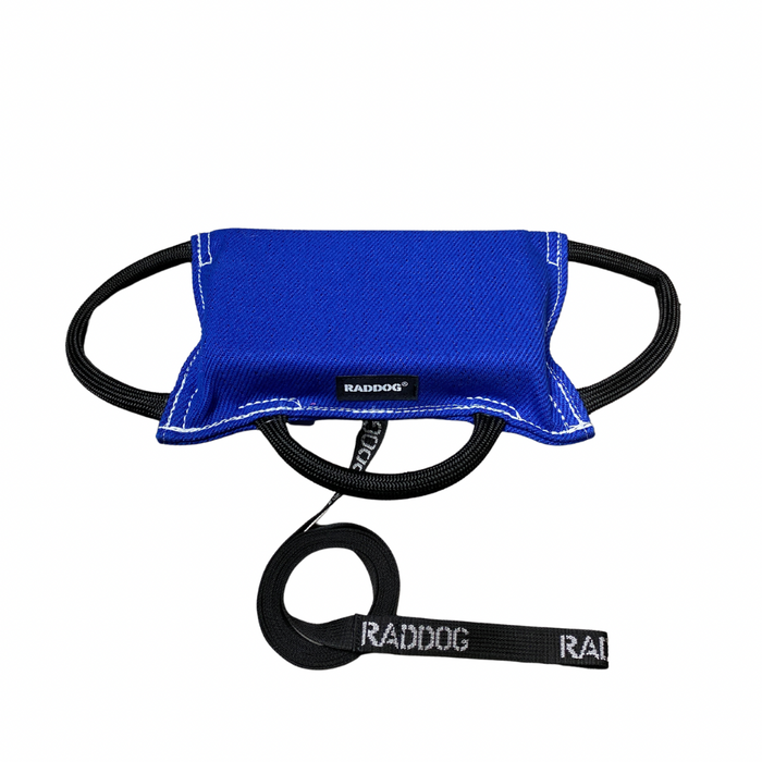 Dark blue dog training bite pad made from durable fabric, featuring reinforced stitching, multiple black loop handles, and a RADDOG logo label, displayed on a white background.