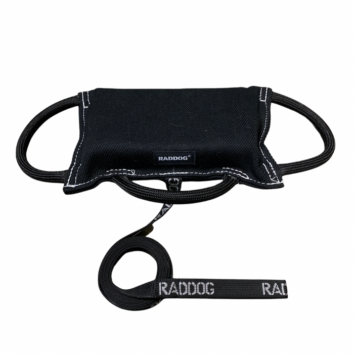 Black dog training bite pad made from durable fabric, featuring reinforced stitching, multiple black loop handles, and a RADDOG logo label, displayed on a white background.