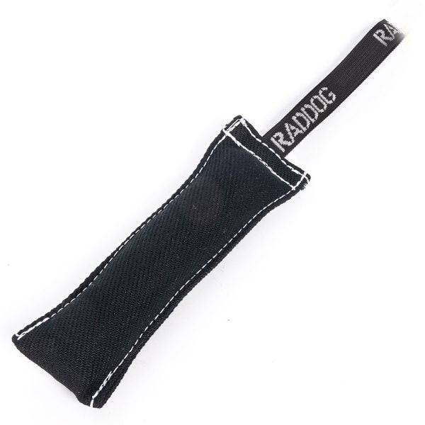 Black cylindrical dog training tug made of durable textured fabric with reinforced stitching, featuring a black loop handle with “RADDOG” branding on one end.