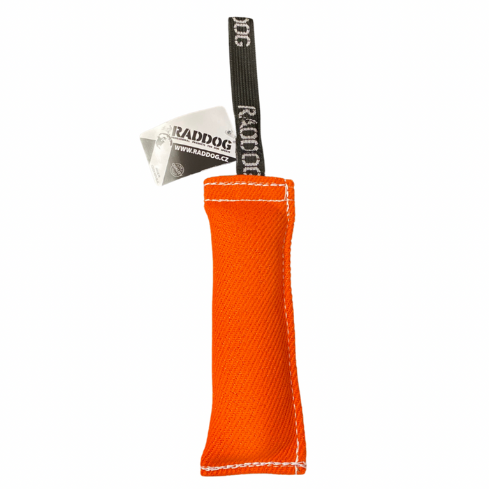 Orange dog training tug toy with a durable textured fabric bite area, reinforced white stitching, and a black loop handle labeled “RADDOG,” with a product tag attached, isolated on a white background.
