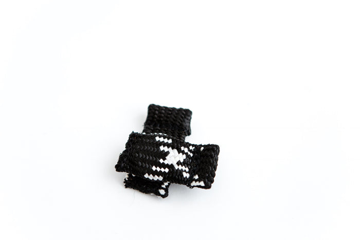 Small black and white woven dog training tug toy with a compact, knotted design, placed on a clean white background.