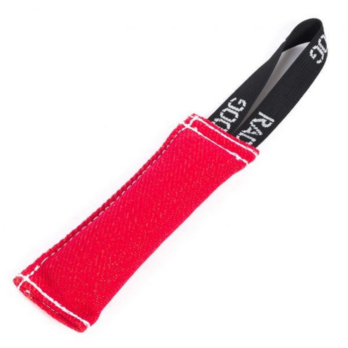 Red padded dog training tug toy with a textured fabric surface, white stitching along the edges, and a black loop handle with white printed text, displayed against a light background.