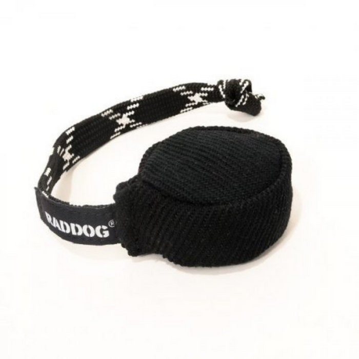 Black fabric dog training puck with a textured woven surface and a black braided handle featuring white “RADDOG” branding, isolated on a white background.