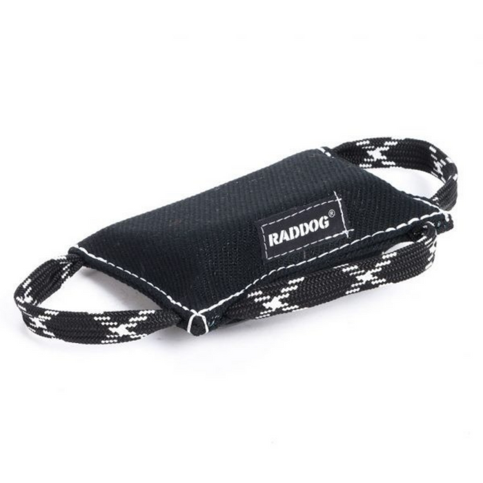 Black dog training bite wedge made of durable textured fabric with reinforced white stitching and two black-and-white patterned handles, featuring a “RADDOG” label, isolated on a white background.