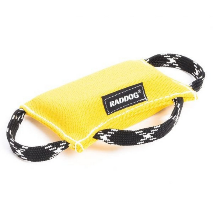 Yellow dog training bite wedge made of durable textured fabric with reinforced white stitching and two black-and-white patterned handles, featuring a “RADDOG” label, isolated on a white background.