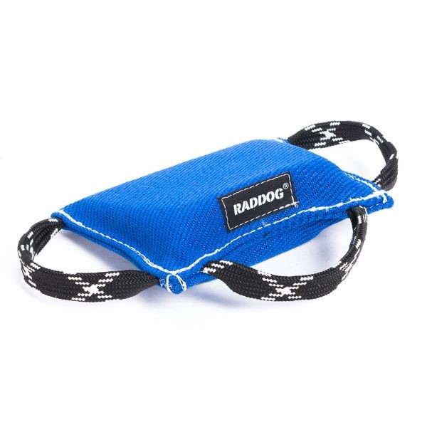 Blue dog training bite wedge made of durable textured fabric with reinforced white stitching and two black-and-white patterned handles, featuring a “RADDOG” label, isolated on a white background.