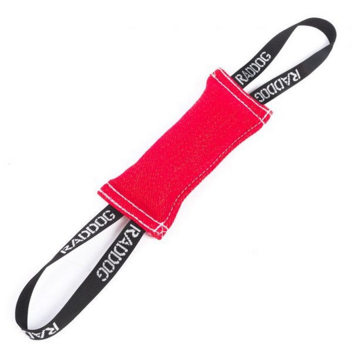 Red dog training tug toy made of durable fabric with white stitching and two black loop handles labeled “RADDOG,” isolated on a white background.