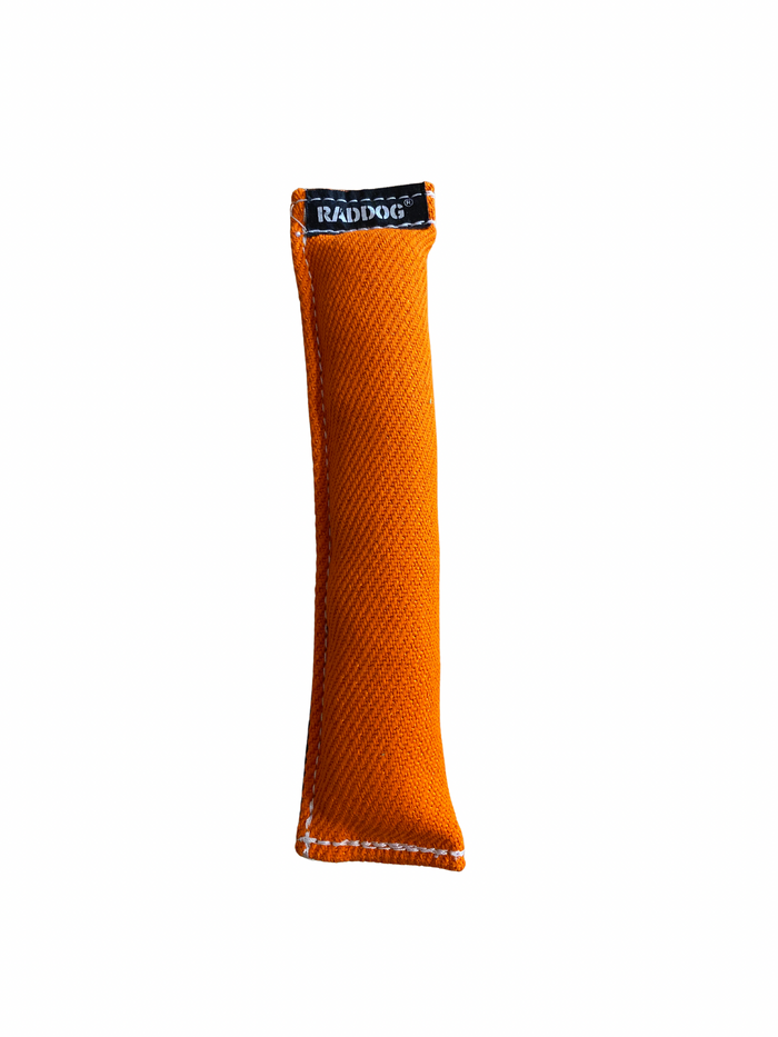 Orange cylindrical dog training tug made of durable woven fabric with reinforced stitching and a black “RADDOG” label on one end.