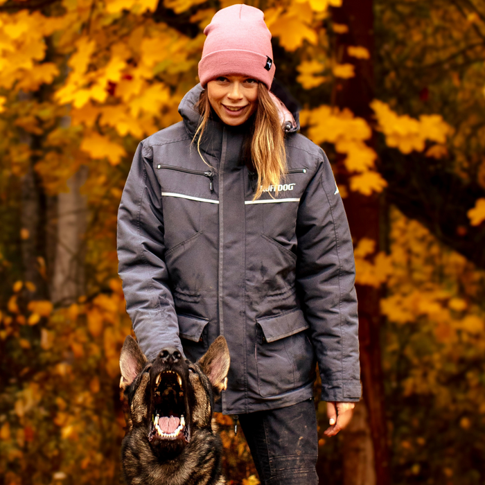 A female dog trainer wearing a dark grey dog trainer jacket loaded with pockets