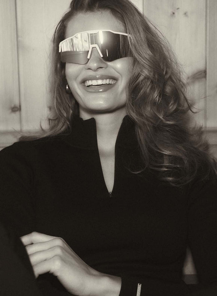 Hopeiset peililinssilliset wrap-around-malliset Pace Sunglasses merkiltä aim'n hymyilevän naisen yllä.