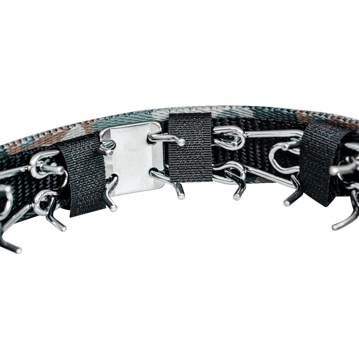 Close-up of a prong dog collar with camouflage cover, showing metal prongs, chain links, and black securing straps against a dark background.